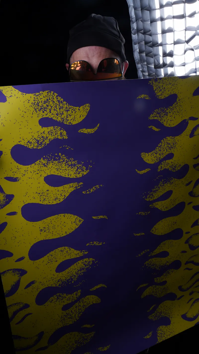 Superfoodman manipulant un fond graphique violet et jaune en studio photo chez Allogood